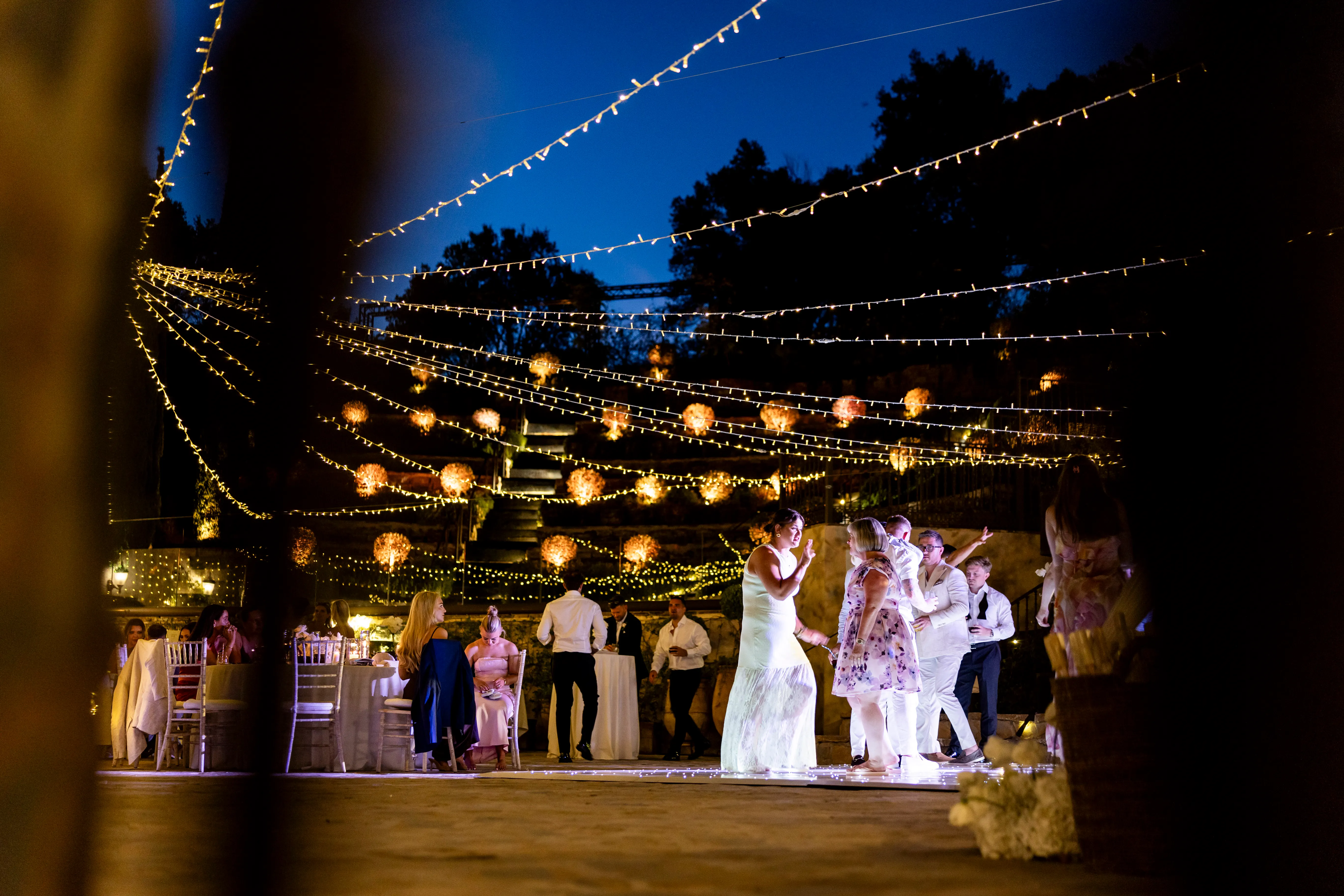 Guests dancing under a canopy of festoon and fairy lights at a Costa del Sol wedding at dusk